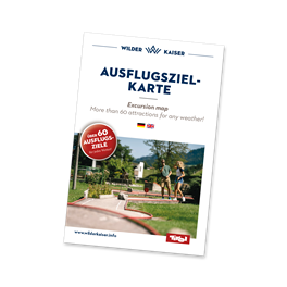 Eine Ausflugszielkarte mit Informationen über Sehenswürdigkeiten. Im Hintergrund sind grüne Landschaften und ein blauer Himmel zu sehen.