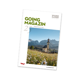 Ein Magazincover mit dem Titel "GOING MAGAZIN". Im Hintergrund sind Berge und eine Kirche in einer blühenden Landschaft zu sehen.