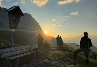 Ein malerischer Sonnenuntergang über den Bergen. Menschen genießen die Aussicht auf dem Weg.