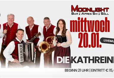 Eine Band in traditioneller Tracht steht für ein Foto zusammen. Sie spielen verschiedene Instrumente, darunter Trompete, Klarinette und Akkordeon.