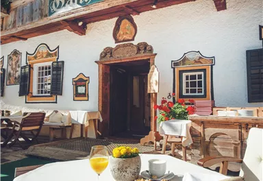 Ein einladendes Gasthaus mit einem schönen Außenbereich und blühenden Blumen. Auf dem Tisch stehen Frühstücksteller und Getränke bereit.