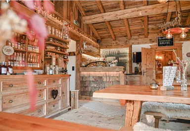 Eine gemütliche Holzbar mit einem einladenden Interieur. Im Hintergrund sind Regale mit Getränken und eine schöne Theke zu sehen.