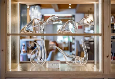 Eine elegante Vitrine mit mehreren kunstvollen Glasobjekten. Die Formen sind modern und transparent, ideal für eine stilvolle Präsentation.