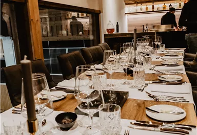 An elegantly set table in a cozy restaurant. The atmosphere is warm and inviting, with wooden decor and beautiful table decorations.