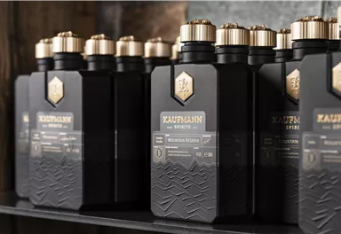 A series of elegant black bottles with gold caps. The bottles are arranged on a shelf and showcase a modern design.