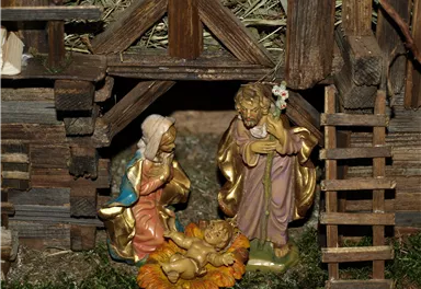 Eine Krippe mit Figuren, die die Geburt Jesus darstellen. Die Szene zeigt Maria, Joseph und das neugeborene Kind in einer liebevoll gestalteten Umgebung.
