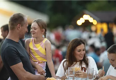 A cheerful family sits together and enjoys a meal. Children laugh and have fun together.