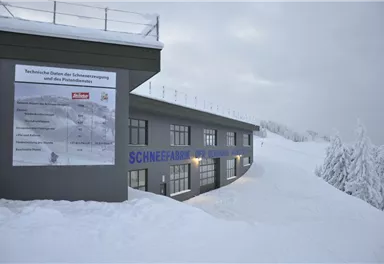 A modern building in a snowy landscape. Signs with technical information about snow production are visible.