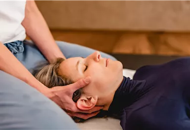 Eine Person erhält eine entspannende Massage im Nackenbereich. Die Atmosphäre wirkt beruhigend und friedlich.