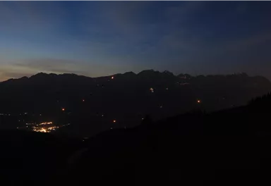 Eine Berglandschaft bei Dämmerung mit schwachem Licht. Am Horizont sind die Silhouetten der Berge zu sehen.