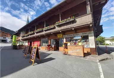 Ein schönes Holzgebäude mit blühenden Blumenkästen. Draußen stehen Schilder für eine Outdoor-Buchungsstelle.