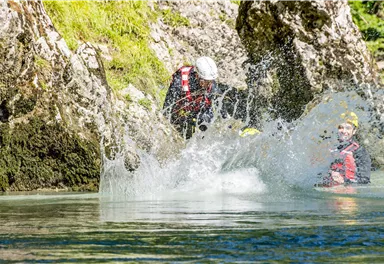 Eine aufregende Wassersportaktivität in einer klaren Gewässerlandschaft. Zwei Personen im Wasser, dabei spritzt Wasser von einem Sprung.
