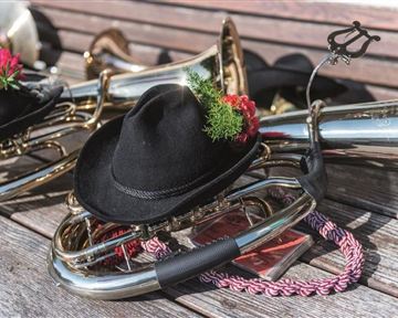 Eine Ansammlung von Blasinstrumenten auf einer Holzoberfläche. Einige Instrumente tragen schwarze Hüte mit Blumen und Dekoration.