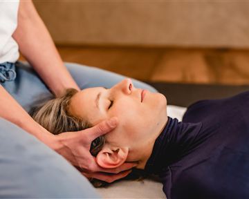 Eine Person erhält eine harmonisierende Massage. Die Anwendung erfolgt sanft und entspannt, während die Person ruhig liegt.