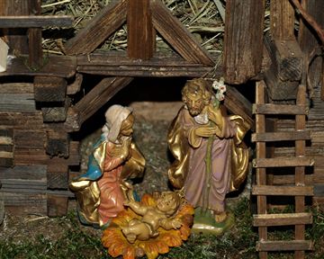 Eine Krippe mit Figuren, die die Geburt Jesus darstellen. Die Szene zeigt Maria, Joseph und das neugeborene Kind in einer liebevoll gestalteten Umgebung.