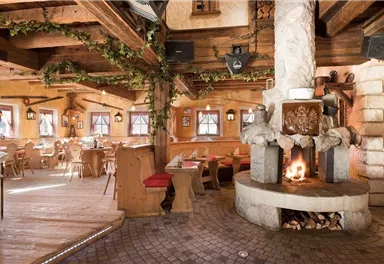 A cozy restaurant with rustic decor and a fireplace. Wooden shelves and warm colors create an inviting atmosphere.