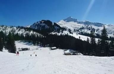 Schneebedeckte Berge unter einem klaren blauen Himmel. Ski- und Freizeitaktivitäten in einer malerischen Winterlandschaft.