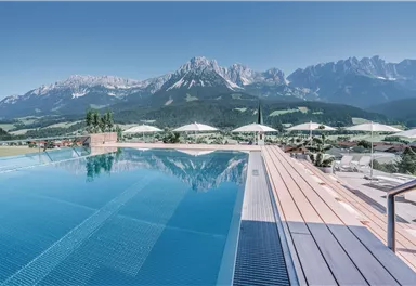 A breathtaking infinity pool with a view of the impressive mountains. Clear skies and umbrellas create a relaxing atmosphere.