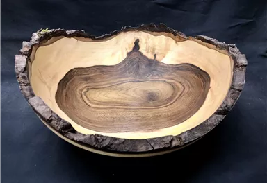 A beautiful wooden bowl with a natural, irregular edge. The grain of the wood is clearly visible and gives the bowl a unique character.