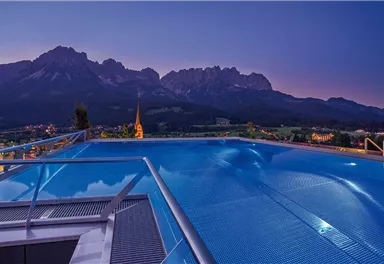 A beautiful infinity pool with a view of the mountains at dusk. The scenery is picturesque and invites relaxation.