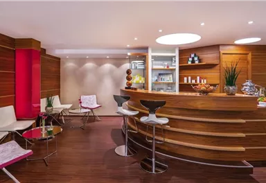 Ein eleganter Empfangsbereich mit einer Holztheke. Moderne Sitzmöbel und dekorative Elemente schaffen eine einladende Atmosphäre.