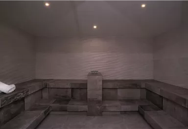 A modern steam bath with gray walls and benches. It is simple and inviting, ideal for relaxation.