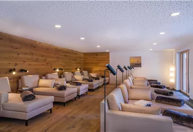 A peaceful relaxation room with comfortable loungers and soft lighting. The wooden walls create a cozy atmosphere.