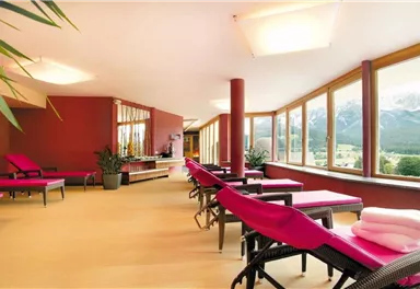 A bright relaxation room with pink loungers and large windows. The view offers a beautiful sight of the mountains.