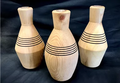 Three decorative wooden vases with black lines in a modern design. They are made of light wood and have different shapes.