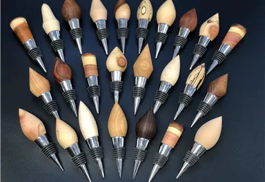 A collection of wooden bottle caps in various shapes and colors. Each cap has a silver rim and is uniquely designed.