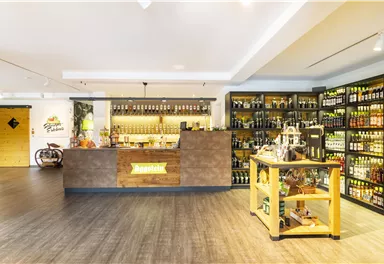 A modern shop with a well-stocked bar and shelves full of drinks. The wooden shelves and the reception counter create an inviting atmosphere.