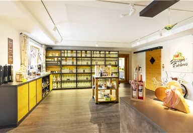 An inviting sales room with shelves full of bottles and products. There is a counter and a charming decoration area.