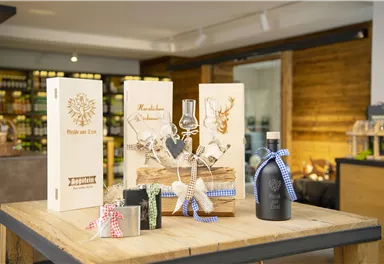 A decorative table with various gift packages and a bottle. The packages are made of wood and feature beautiful designs.