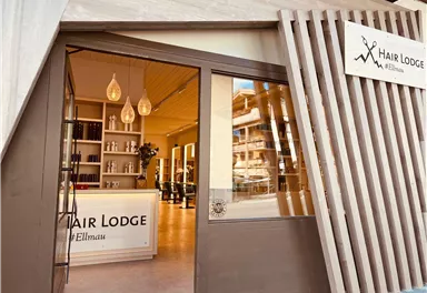 Ein moderner Friseursalon mit dem Namen "Hair Lodge" in Ellmau. Die Eingangstür ist einladend und zeigt einen hellen, minimalistischen Innenraum.