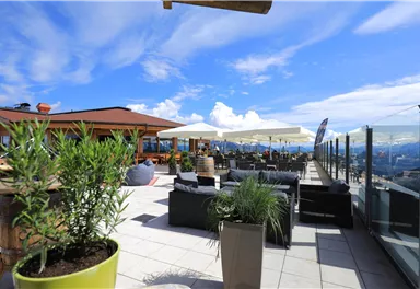 An inviting rooftop terrace with modern seating and sun umbrellas. In the background, a clear sky and a beautiful view stretch out.