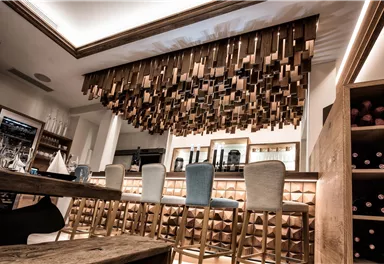 An elegant bar with a modern wooden decor and stylish bar stools. The atmosphere is friendly and inviting.
