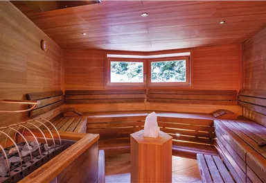 Eine gemütliche Sauna mit Holzverkleidung und Fenster, die einen Blick nach draußen bieten. Der Raum ist einladend und ideal zum Entspannen.
