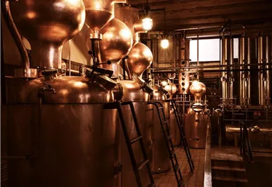 A distillery with several copper distillation columns. The warm light creates an inviting atmosphere.