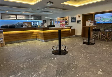 A modern reception area with a wooden counter and bright lighting. In the background, images and a slideshow can be seen.