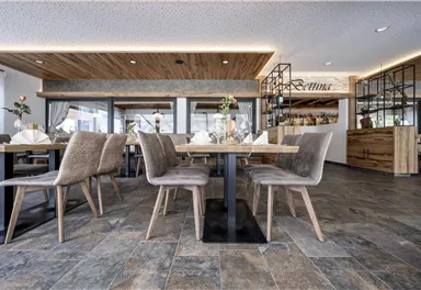 Ein stilvolles Restaurant mit modernen Tischen und Stühlen. Das Interieur ist hell und einladend, mit einer eleganten Bar im Hintergrund.