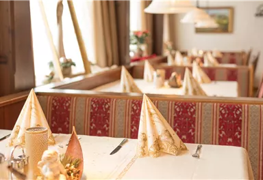 An elegant restaurant area with festively laid tables. The tablecloths are white, and the napkins are artistically folded.