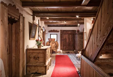 Ein gemütlicher Flur mit Holzmöbeln und einem roten Teppich. Die Wände sind aus Holz, und es gibt eine warme, einladende Atmosphäre.
