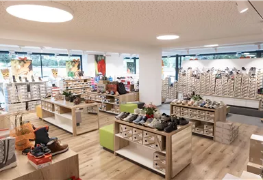 Ein moderner Schuhladen mit hellen Regalen und verschiedenen Schuhmodellen. Die Atmosphäre ist einladend und gut beleuchtet.