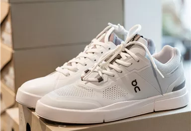 Ein Paar weiße Sneakers auf einem Stapel Schuhkartons. Die Schuhe haben ein modernes Design und sind für den Alltag geeignet.