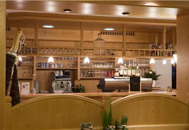 Eine gemütliche Bar mit Holzregalen und einer Auswahl an Getränken. Die warmen Lichter schaffen eine einladende Atmosphäre.