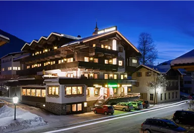 Ein einladendes Hotel im Schnee, beleuchtet bei Nacht. Die Umgebung ist ruhig mit einer klaren Bergkulisse.