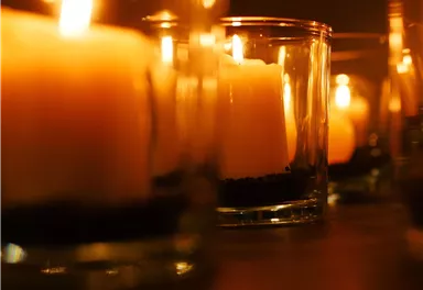 Candles in glass containers softly glow in the dark. Their warm flames create a cozy atmosphere.