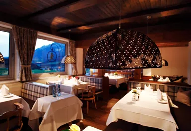 A stylish restaurant with elegant lighting and tables set for guests. In the background, a picturesque landscape can be seen.