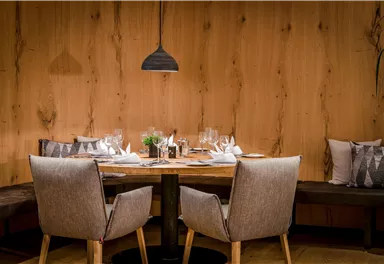 A stylish restaurant with a wooden table and elegant chairs. The table decoration is simple and appealing, creating an inviting atmosphere.