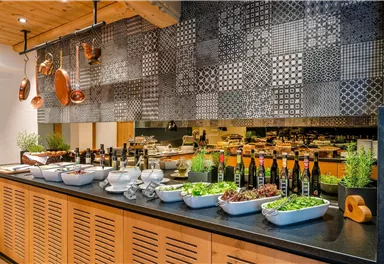 An elegant buffet area with various fresh ingredients and oils. Decorative patterns can be seen on the wall, creating an appealing atmosphere.